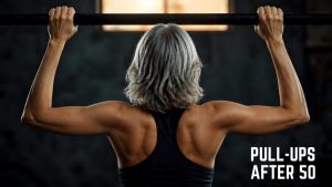 Fit mature woman performing a neutral grip pull-up on a pull-up bar to demonstrate safe upper-body strength training after 50